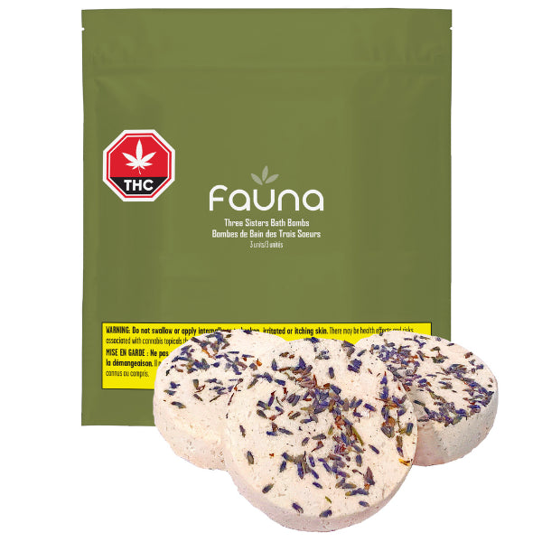 The image shows a package labeled 'Fauna' with a cannabis leaf logo and text indicating it is a product with THC. There are three bath bombs outside the package, adorned with lavender petals, and the package warns about potential side effects.