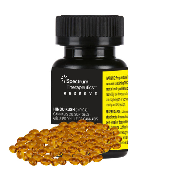 A bottle of Spectrum Reserve Hindu Kush Softgels with a label indicating it is a product of Spectrum Therapeutics. The bottle is accompanied by several orange softgel capsules spilling out in front of it.