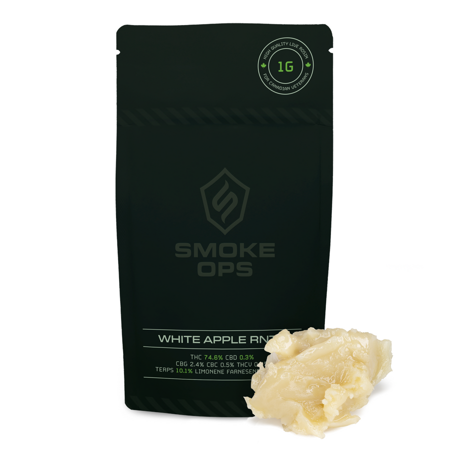 A black Smoke Ops White Apple Rind edible product pouch shown on a white background with a small pile of pale yellowish edible wax melt in front. The pouch has a circular seal at the top right and visible Smoke Ops branding.