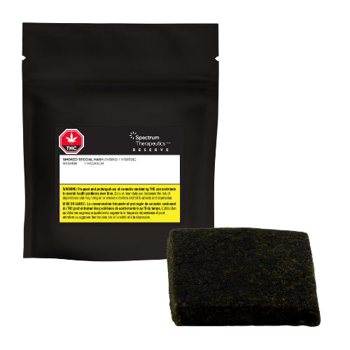 A dark, solid-colored rectangular hashish with black packaging in the background