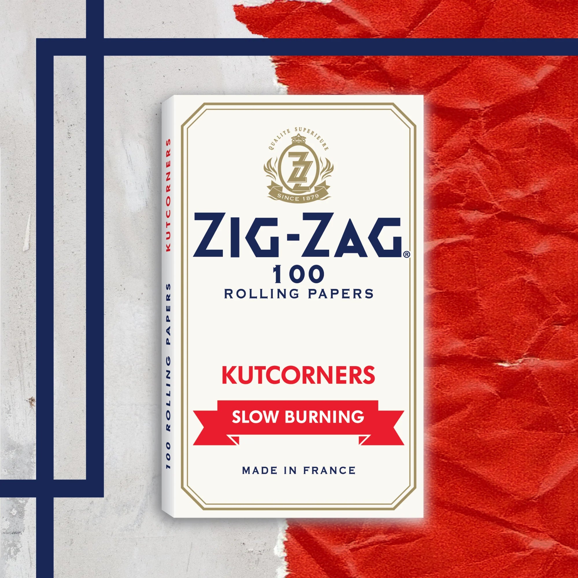 Packaging of Zig-Zag 100 rolling papers with 'Kutcorners' and 'Slow Burning' text, featuring a white background with red and blue accents and a logo at the top.