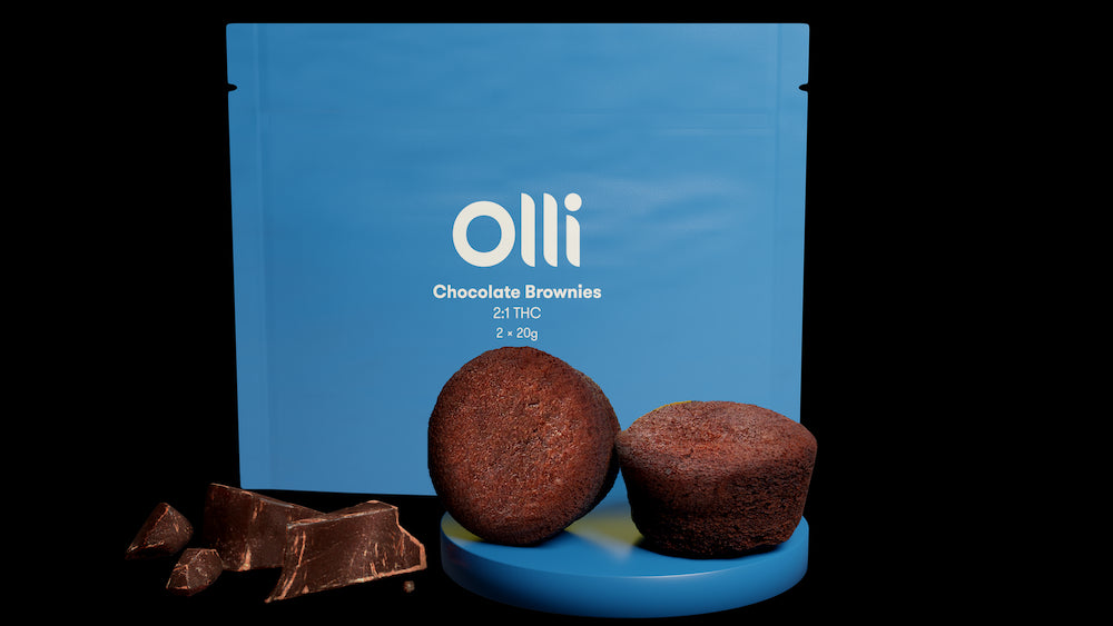 A packaged product labeled 'Olli Chocolate Brownies' with two brownies in front of the package and pieces of chocolate broken off to the side.