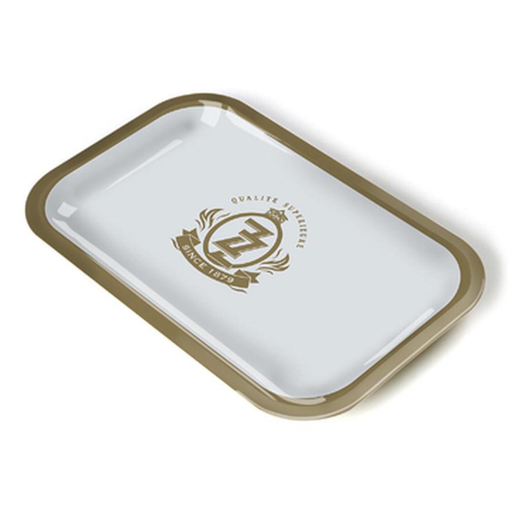 A small rectangular metal rolling tray with high edges, featuring a glossy white surface and the Zig Zag logo in gold at the center.