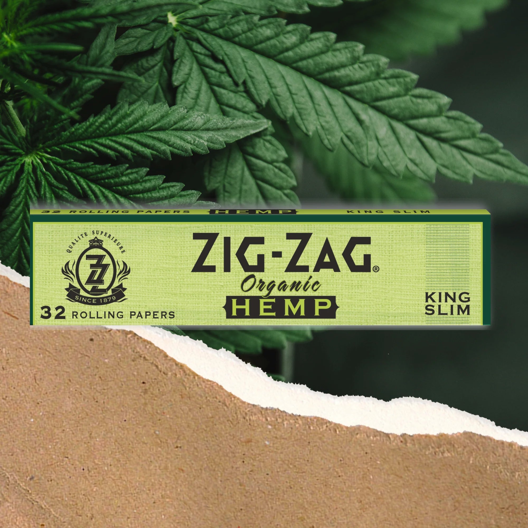 A pack of Zig-Zag Organic Hemp King Slim Rolling Papers placed against a background with cannabis leaves.