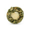 A round, cross-section style product shot on a white background, showing a textured outer ring of dried green plant material with orange flecks and a pale cream center.