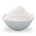 A mound of coarse white sugar piled in a small white ceramic bowl on a clean white background.