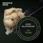 A close-up of a beige gummy or wax-like product on a black spoon against a dark background, with a circular label reading 'ORZ SUPREME' and 'THC 75.8%' plus 'SMOKE OPS' text at top left.