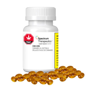 A bottle of Spectrum Therapeutics brand softgels, with a label indicating CBD:CBN 2:1 ratio, and a concentration of 20mg CBD and 10mg CBN per softgel. The bottle is accompanied by several orange capsules spilling out in front.