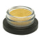 Small glass container with gold powder on a black base against a white background