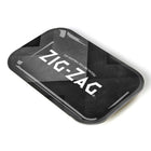 A small rectangular metal rolling tray with high edges, featuring a glossy black surface and the Zig Zag logo in white at the center.